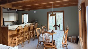 A cozy cabin interior with a dining area, kitchen, and large windows.