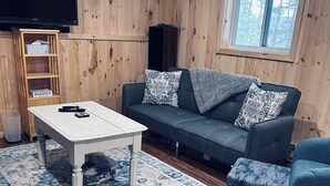 A cozy living room with a sofa, armchairs, a coffee table, and a TV.