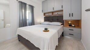 A modern bedroom with a bed, grey curtains, a bedside table with a lamp, and a wardrobe with a mirror. - Villa Julija  ZadarVillas (Sukošan)