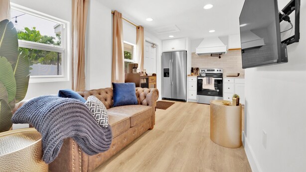 Ein modernes Wohnzimmer mit einer Couch, einem Couchtisch und einem an der Wand montierten Fernseher.