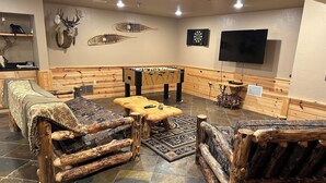 Une pièce rustique, meublée de meubles en bois, avec un baby-foot et une tête de cerf accrochée au mur.