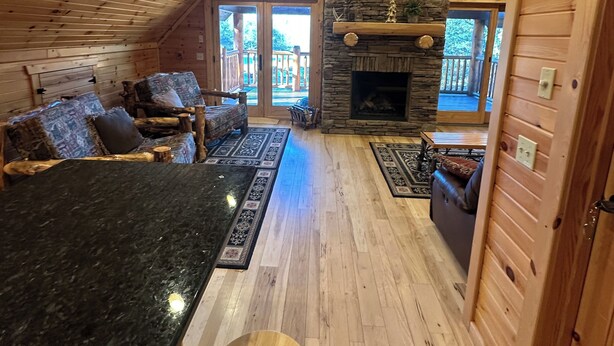L’intérieur chaleureux d’un chalet avec une cheminée en pierre, un plafond en bois et un coin salon doté d’un bar.