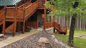 Une cabane en bois dotée d’un porche couvert, de fondations en pierre et d’un chemin de gravier menant à l’entrée.