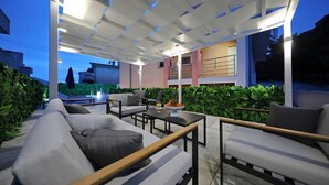 An outdoor patio area with a modern design, featuring a seating arrangement with sofas and tables, surrounded by greenery. - Villa Amarena ZadarVillas (Zadar)