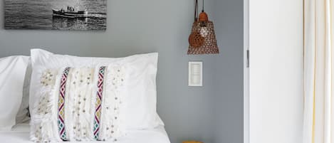 Un dormitorio con cama, una lámpara de pared y un cuadro de un barco en la pared.