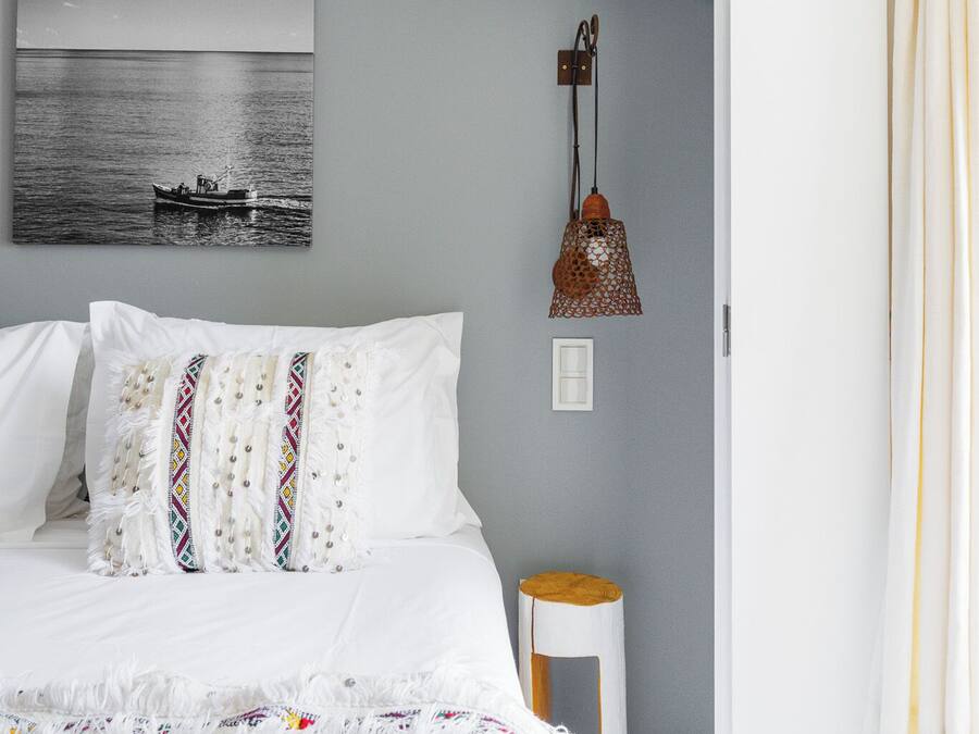 Un dormitorio con cama, una lámpara de pared y un cuadro de un barco en la pared.