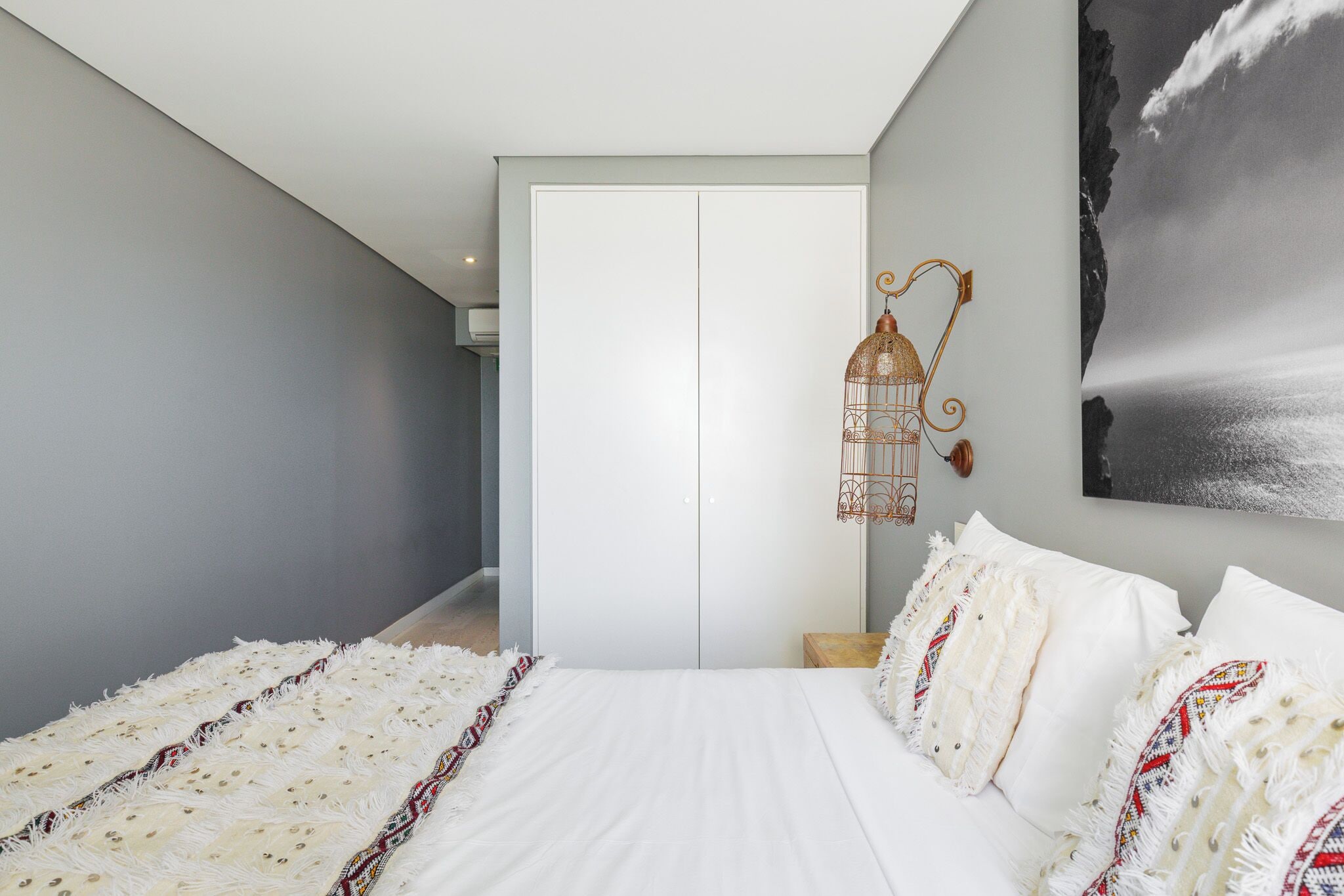 A bedroom with a large bed, a hanging light fixture, and a framed picture on the wall.