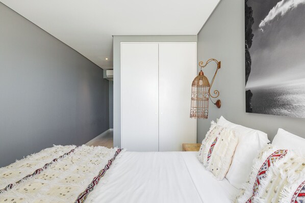 A bedroom with a large bed, a hanging light fixture, and a framed picture on the wall. - Casa da Praça (Sesimbra)