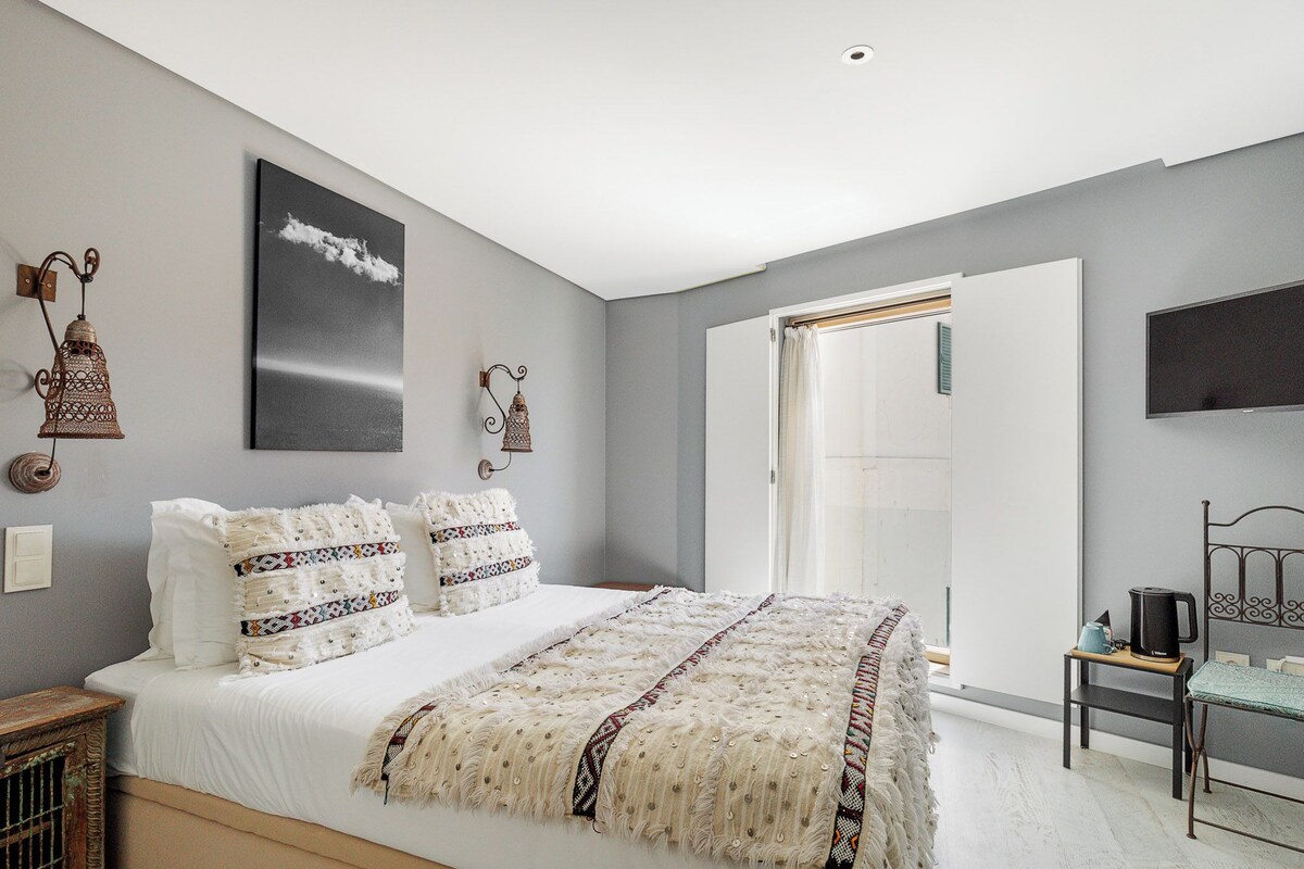 A bedroom with a bed, a television, a coffee maker, and a door leading to a bathroom.