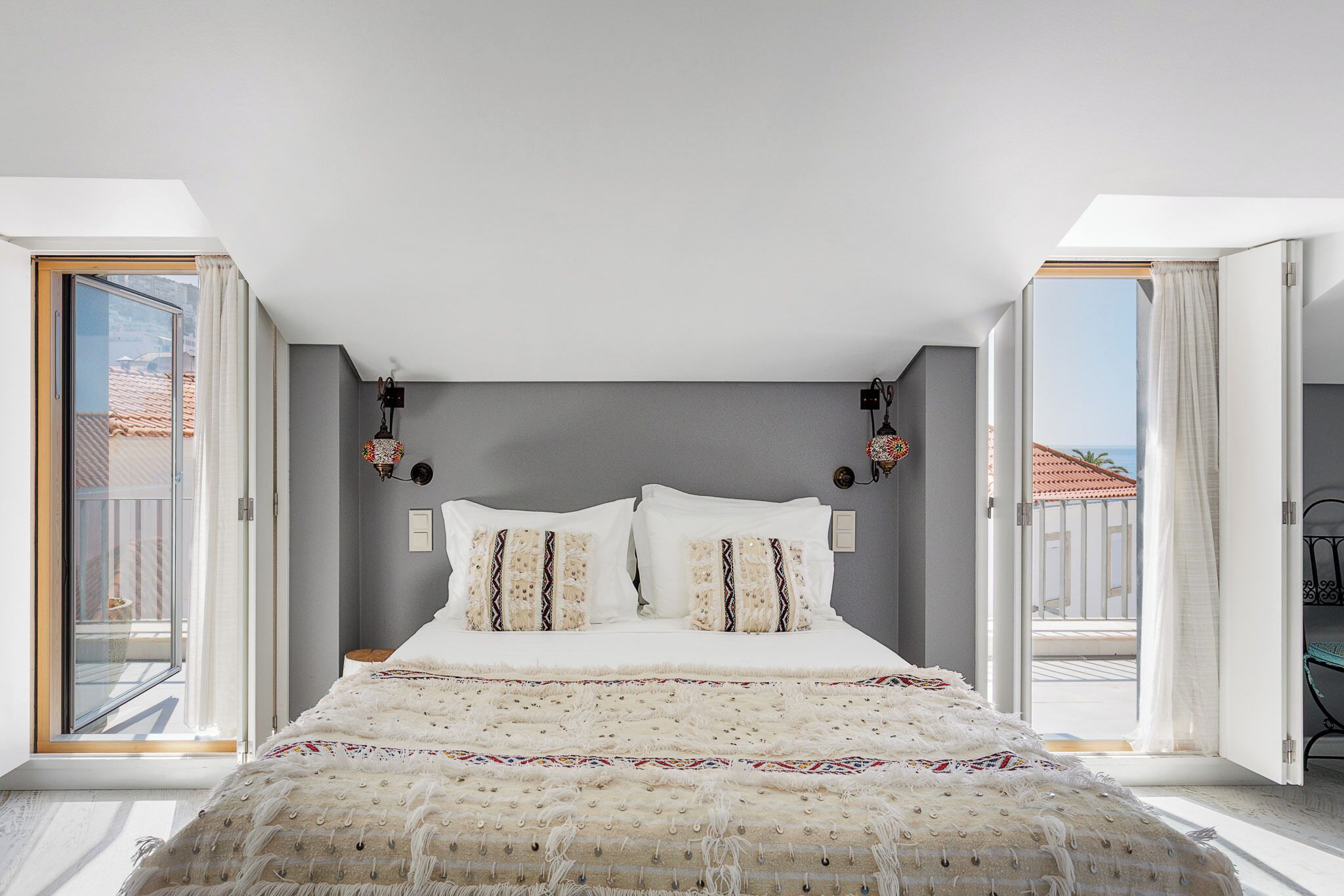 Un dormitorio con una cama grande, dos lámparas de pared y vistas al exterior.