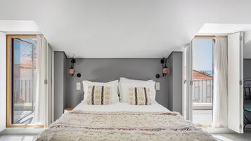 Quarto com cama grande, duas luminárias na parede e vista para o exterior.
