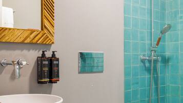 Un baño con un lavabo blanco, un espejo con marco de madera, un inodoro y una ducha con azulejos azules.