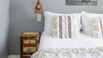 Een slaapkamer met een bed, nachtkastje, een lamp aan de muur en een ingelijste foto.