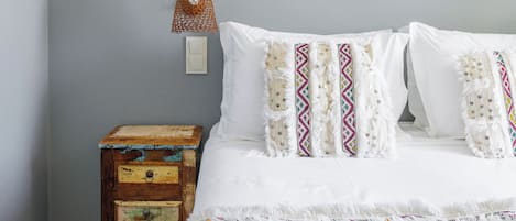 Un dormitorio con cama, mesita de noche, lámpara de pared y un cuadro enmarcado.