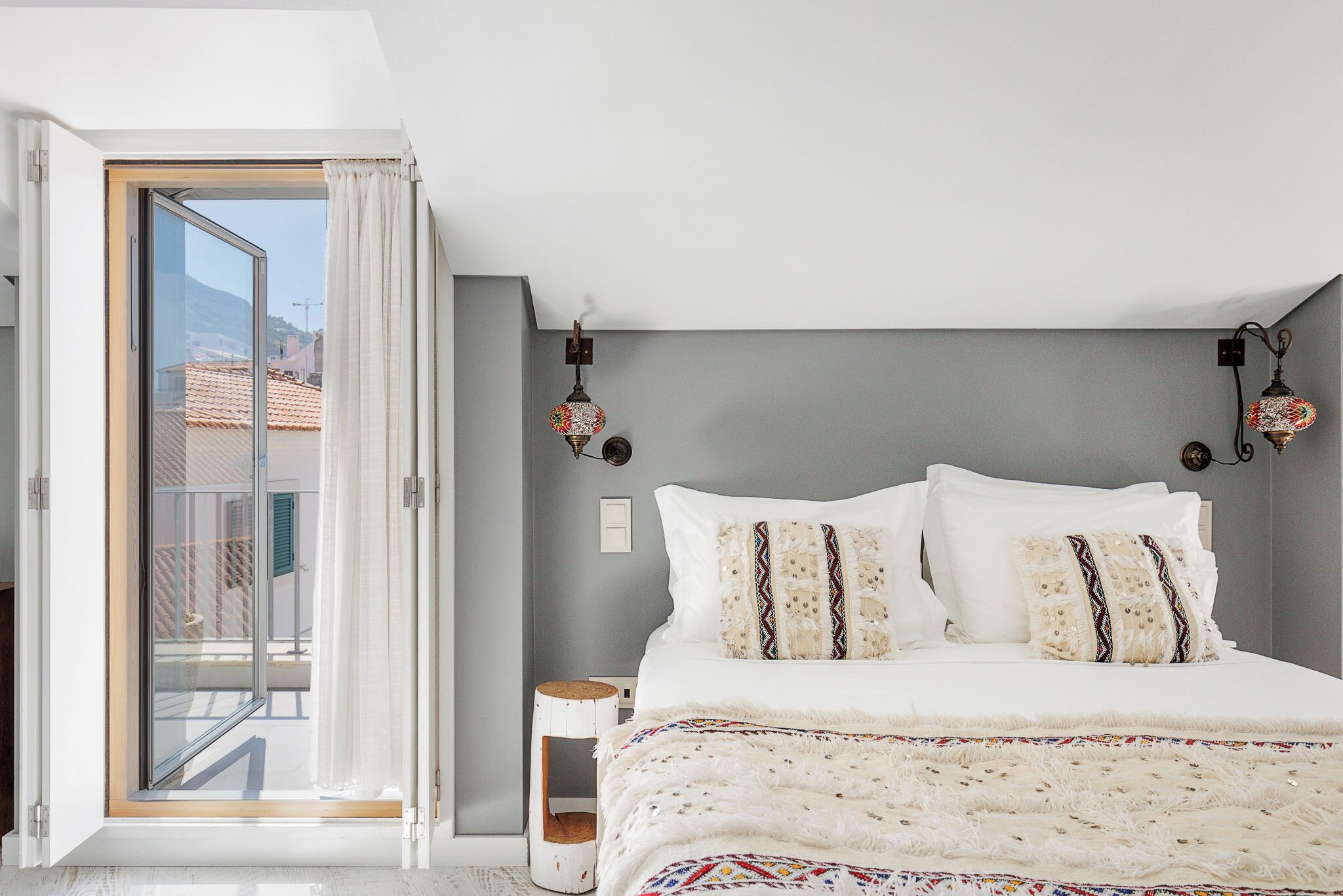 A bedroom with a bed, a nightstand, a lamp, and a view through a sliding door.