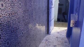 A narrow hallway with patterned walls and a tiled floor, leading to a door.
