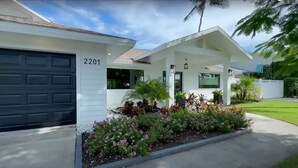 Ein modernes Haus mit Garage mit der Nummer 2201, einer überdachten Veranda und einem gepflegten Garten.