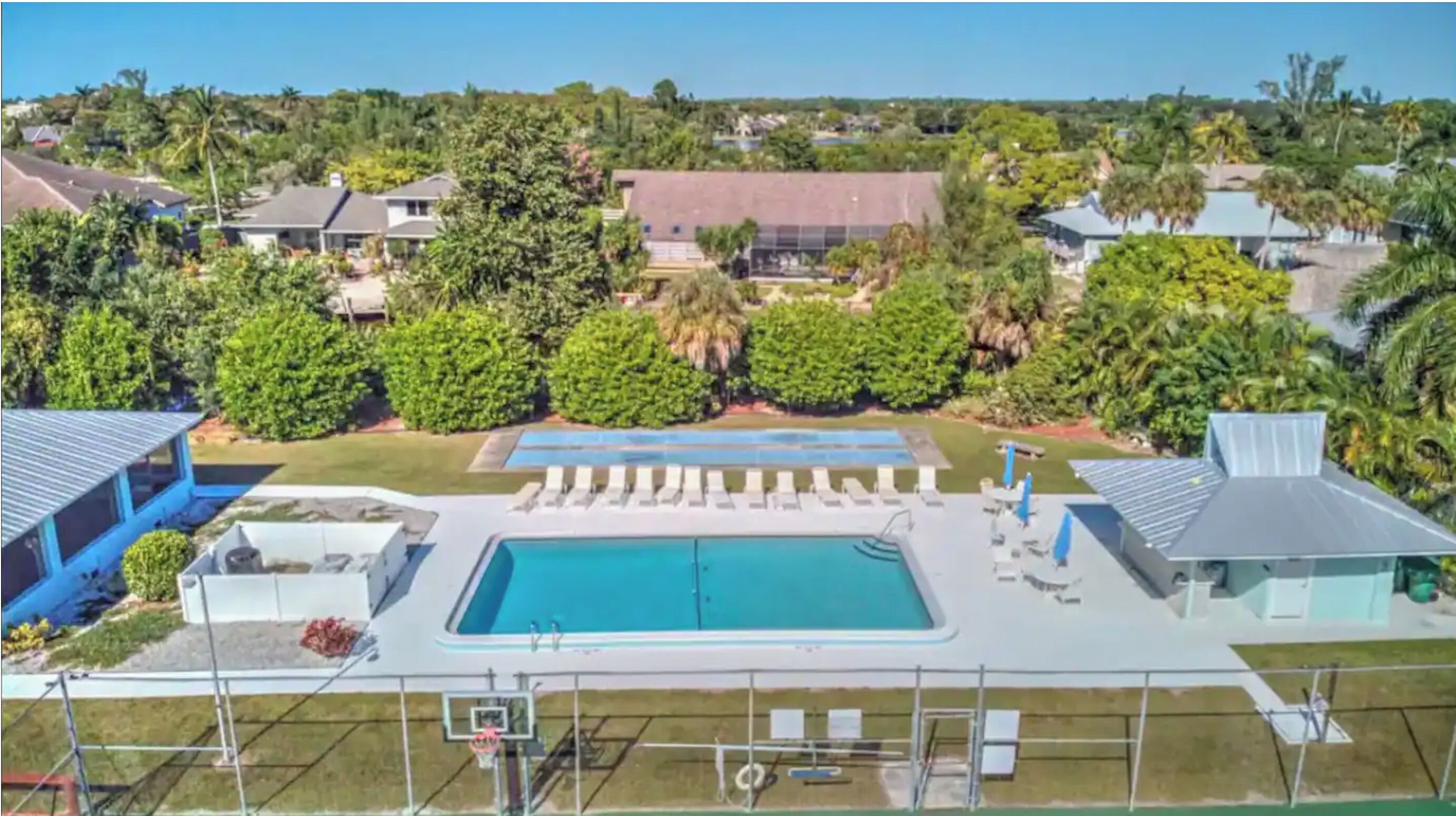 A pool area with multiple pools, lounge chairs, and a basketball court.