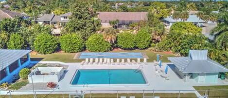 A pool area with multiple pools, lounge chairs, and a basketball court.