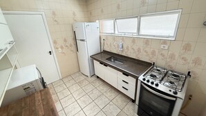 Een kleine keuken met een koelkast, gootsteen, fornuis en oven.