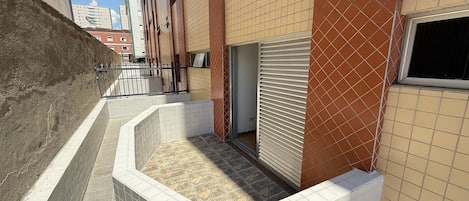 A narrow alleyway with a tiled wall and a small enclosed area with a window.