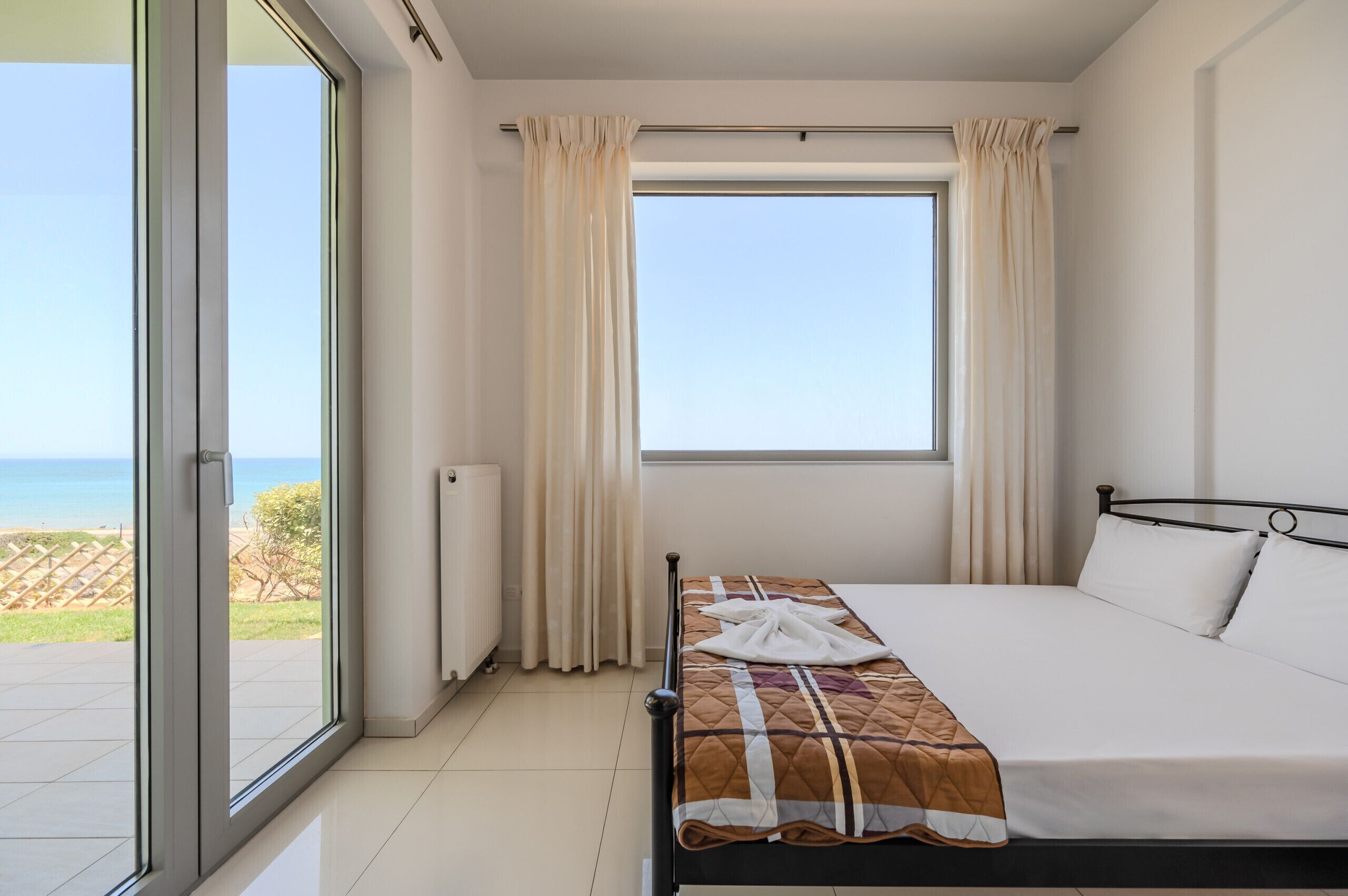 Une chambre d’hôtel avec un lit, une fenêtre avec des rideaux et une vue sur la plage.