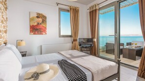 A hotel room with a bed, a TV, a painting, and a balcony with a view of the sea.