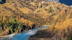 Un fiume serpeggia attraverso un paesaggio montuoso con autunno dai colori caldi.