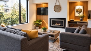 Una sala moderna con chimenea, televisor de pantalla plana y comedor con mesa y sillas de madera.