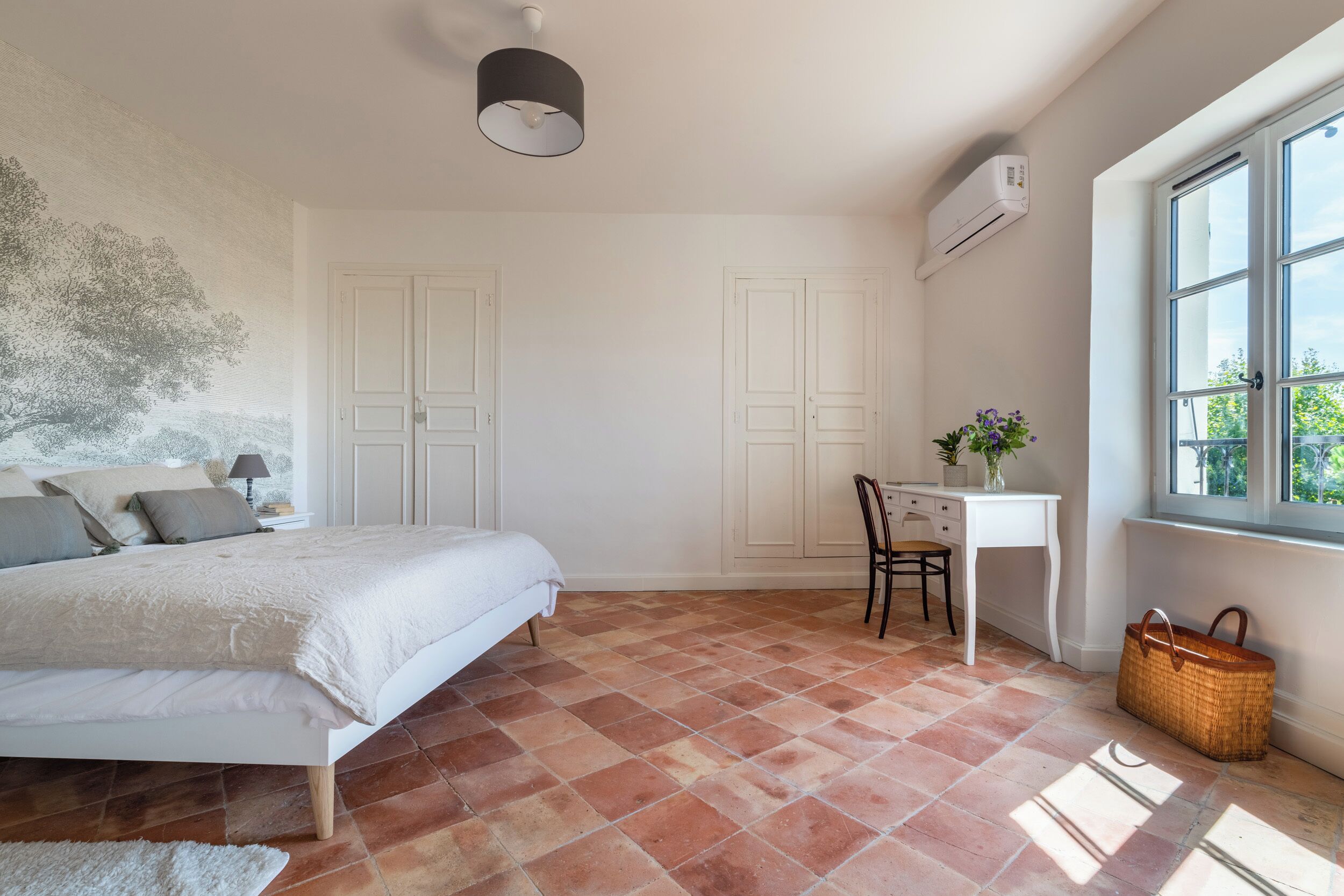 A bedroom with a bed, a desk, and a window.