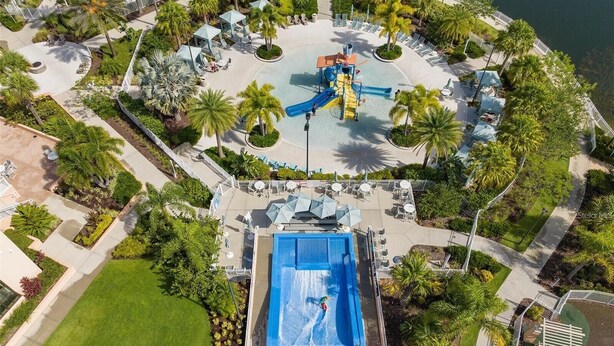 Vista aérea de un complejo turístico con una gran piscina, palmeras y un tobogán de agua.