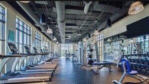 Un gimnasio con cintas de correr, máquinas de pesas y mancuernas.