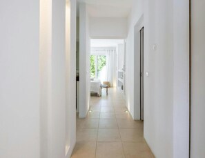 A modern, well-lit hallway with a bed and a small table in the distance, leading to a room with a large window. - Tranquil Villa With Private Pool (Sant Antoni de Portmany)