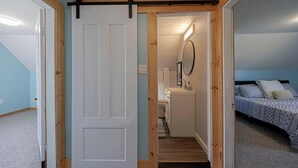 Een slaapkamer met een bed, nachtkastje en spiegel.