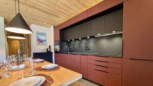 A modern kitchen with wooden cabinetry, a built-in stove, and a dining area set with plates and glasses.