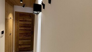 A hallway with wooden paneling, a wooden door, and a small shelf with a light fixture.