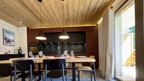 A modern kitchen with dark cabinets, a wooden ceiling, and a dining area with a table set for four.