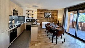 A modern kitchen with a dining area, wooden flooring, and a view of the outdoors. - Large, bright T4 in the heart of Châtel (CHATEL)
