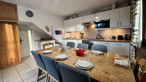 A modern kitchen with white cabinets, a wooden dining table, and a red pot.