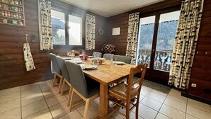 A dining area with a wooden table set for four, surrounded by chairs.