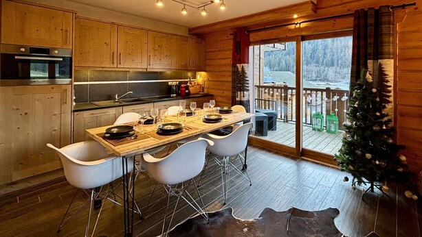 Eine gemütliche Küchenzeile im Chalet-Stil mit Holzschränken, einem Esstisch für vier Personen und einem Weihnachtsbaum.