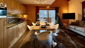 Eine gemütliche Küchenzeile im Blockhausstil mit Holzausstattung, einem Esstisch für vier Personen und einem Weihnachtsbaum.