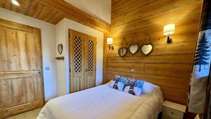 Ein Schlafzimmer mit Holzboden, einem großen Bett mit weißer Bettwäsche, einem Nachttisch und einem an der Wand befestigten Spiegel.