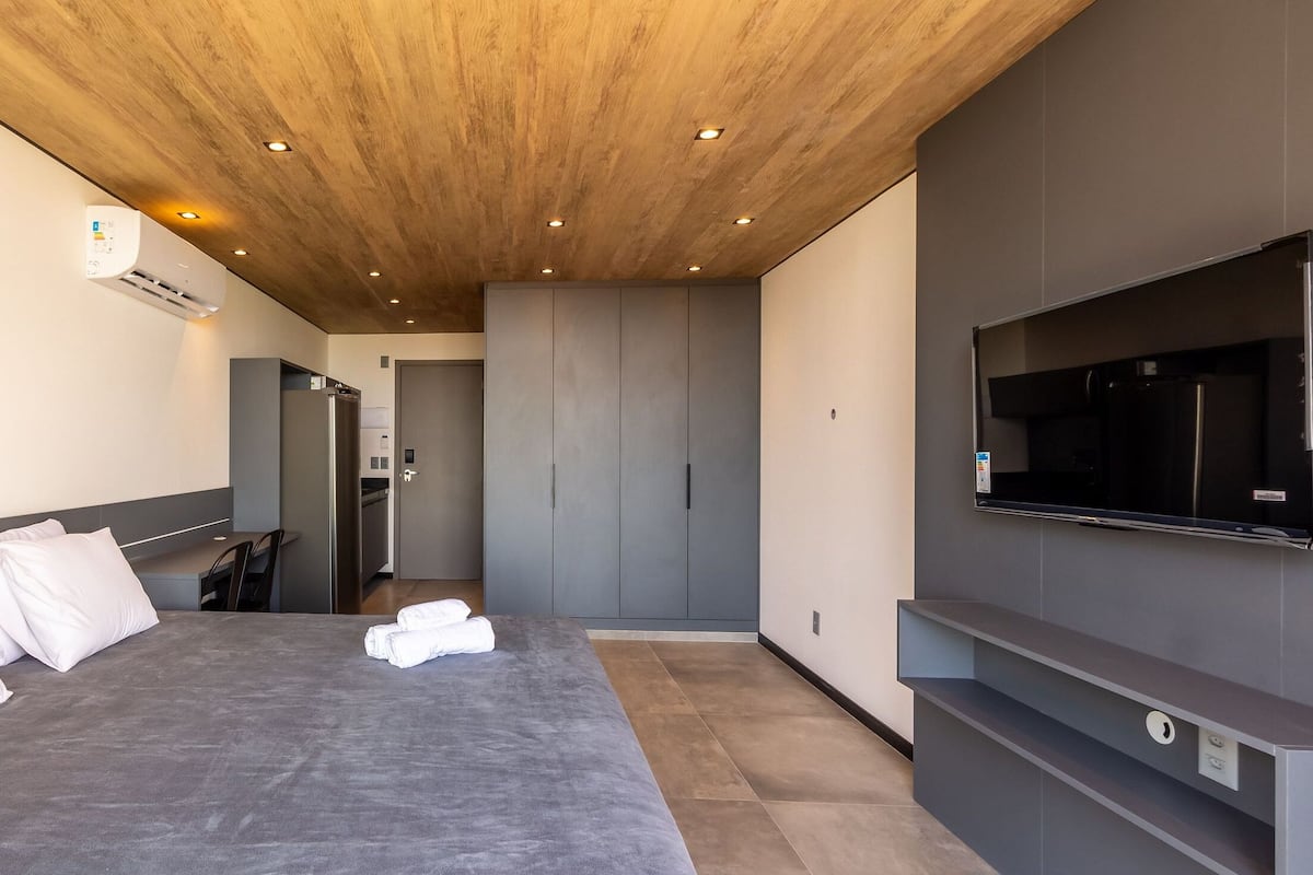 Une chambre d’hôtel moderne dotée d’un grand lit, d’un téléviseur à écran plat fixé au mur et d’une armoire intégrée.