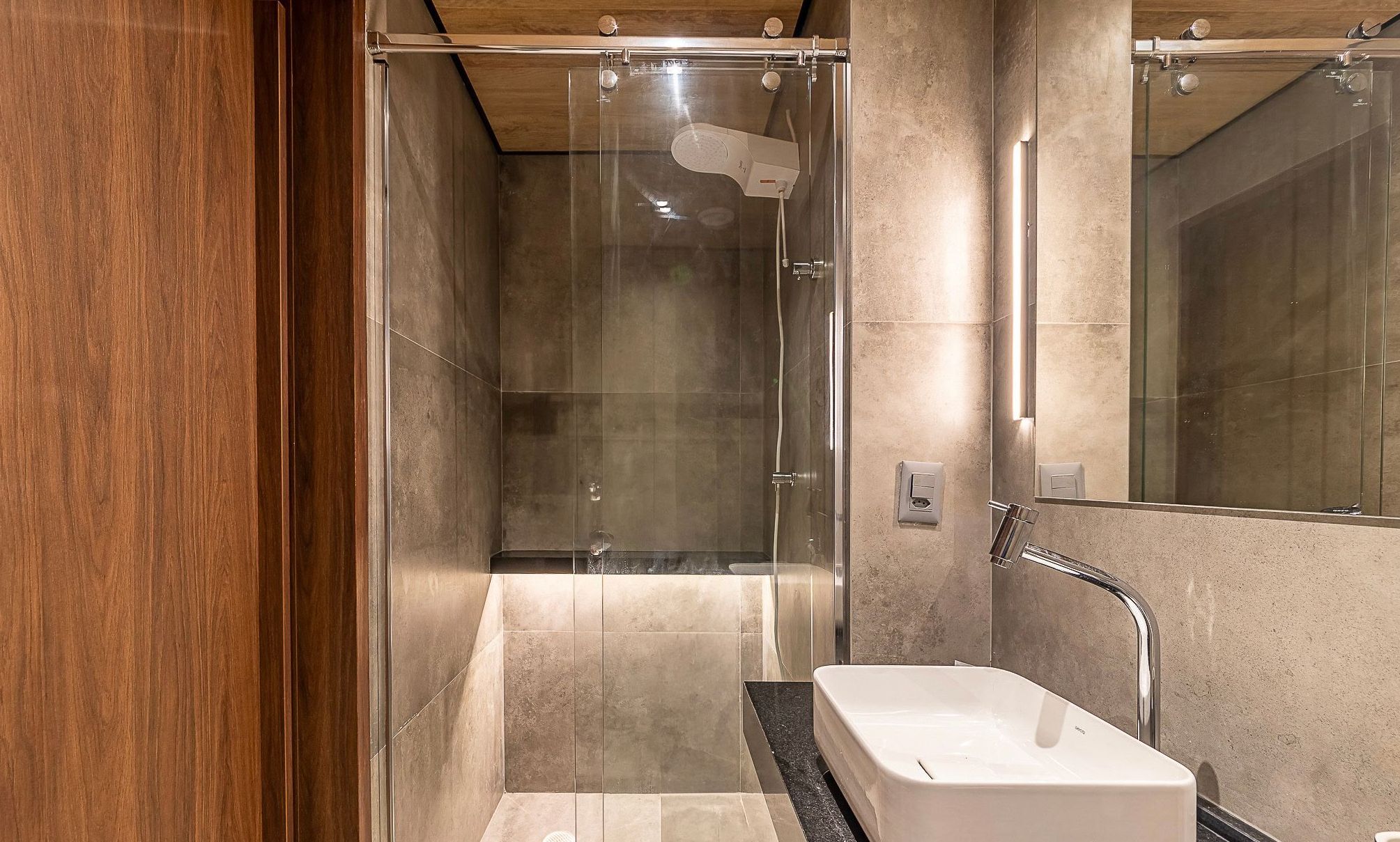 A modern bathroom with a glass-enclosed shower, a white sink, and a large mirror.