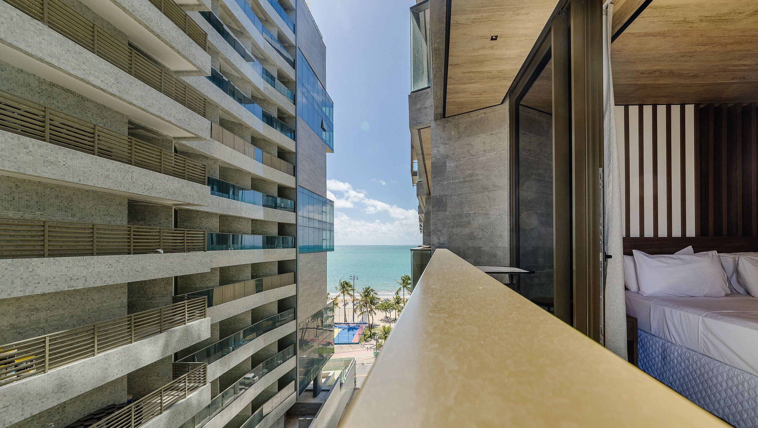 A hotel balcony with a view of the ocean and a pool.
