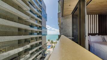 A hotel balcony with a view of the ocean and a pool.