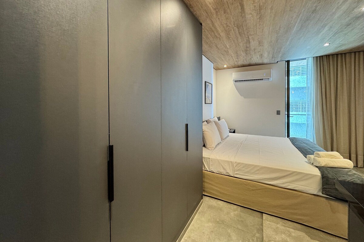 Un dormitorio moderno con una cama grande, un armario y una lámpara en el techo.