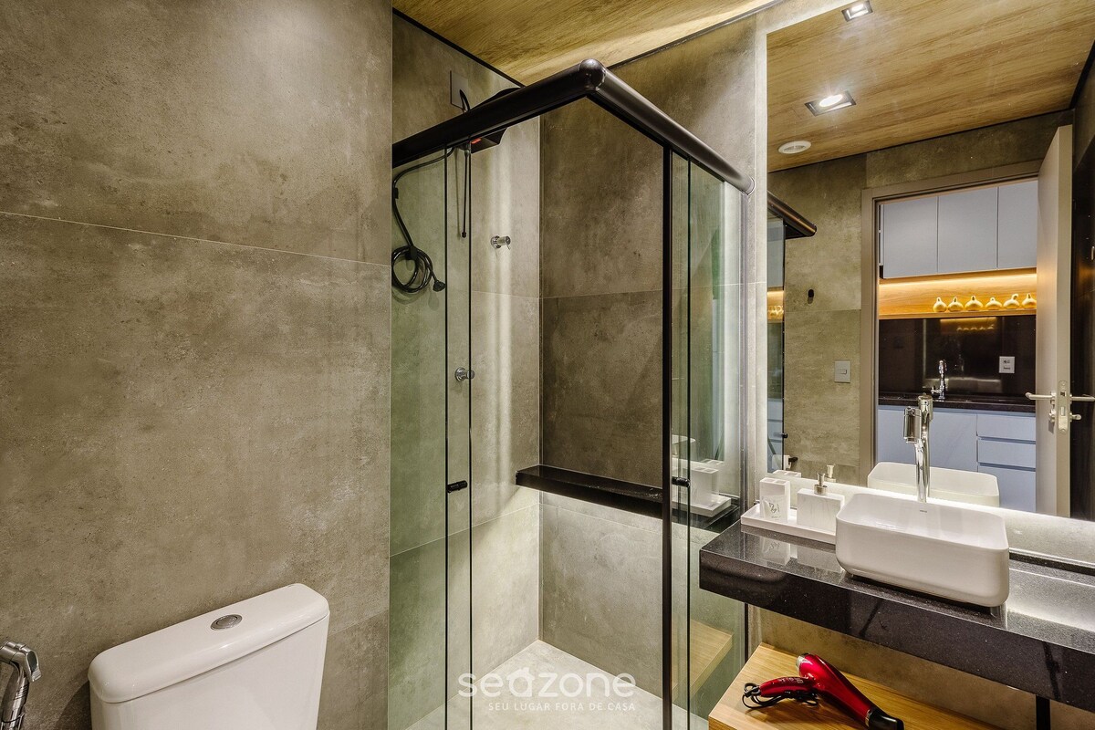 A modern bathroom with a glass-enclosed shower, a white toilet, and a black countertop with a sink and vanity.