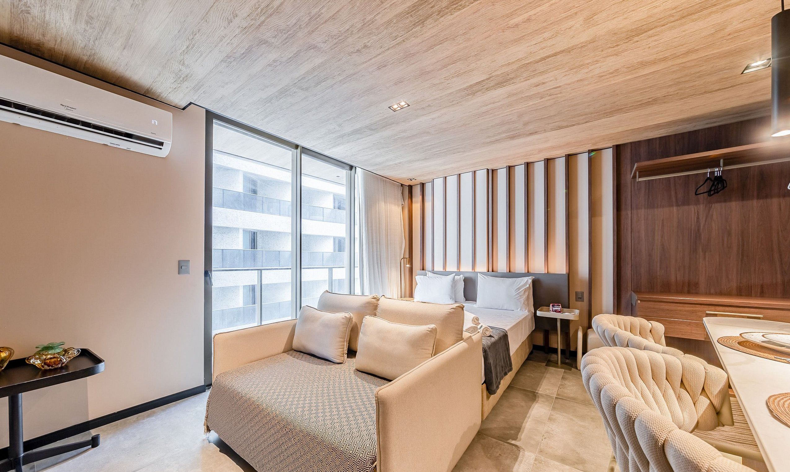 Habitación de hotel moderna con una cama grande, un sofá, una mesita y vistas a la ciudad.